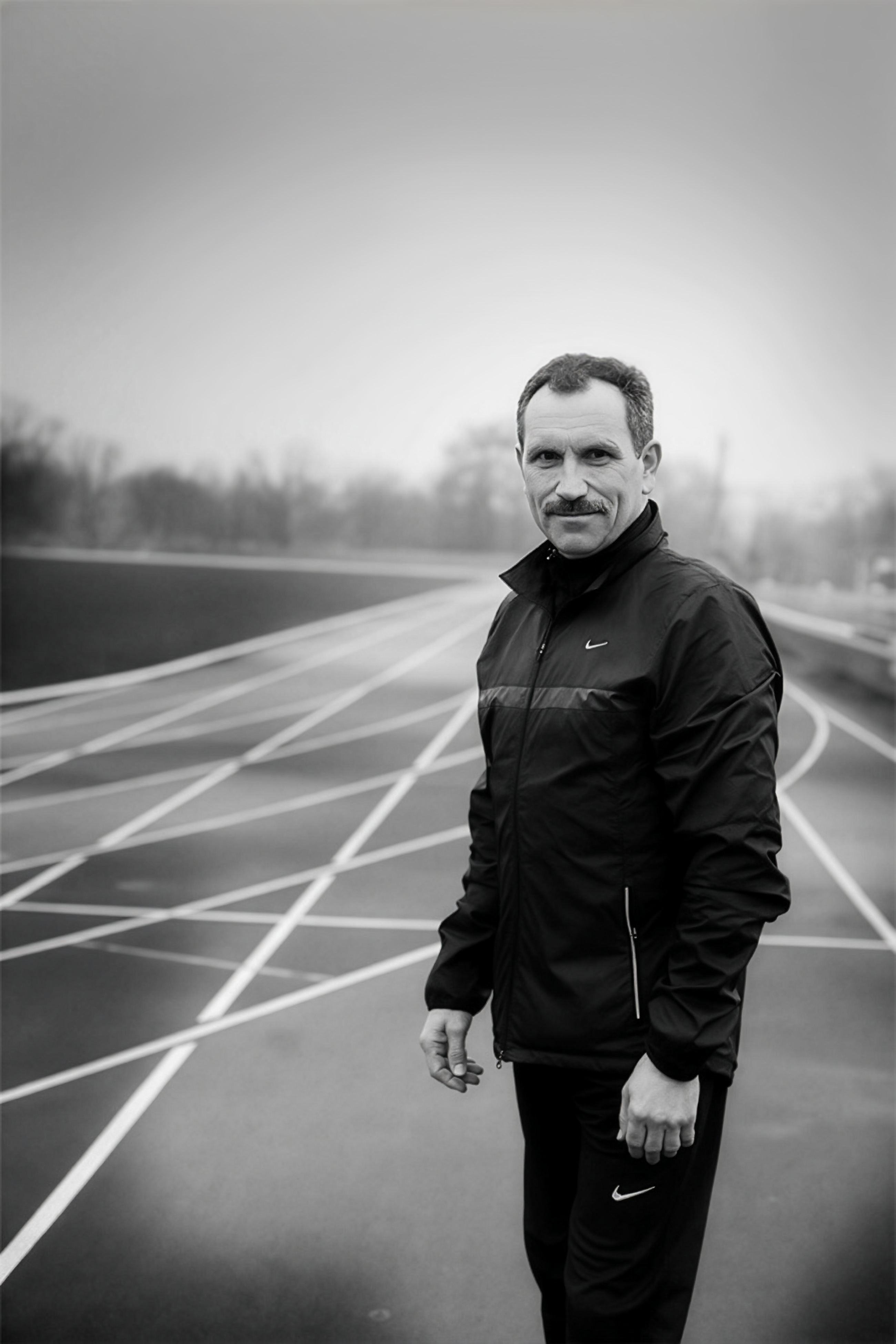 Czarno-biały portret trenera Piotra Kiedrowicza na stadionie